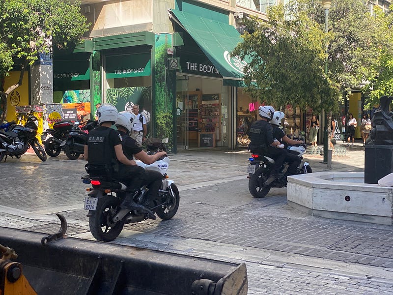 Police officers mounted on motorcycles riding down a street in Athens