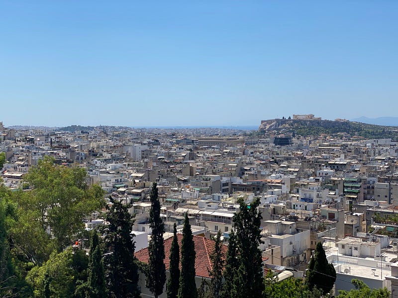 View from a hilltop over the city of Athens with the Acropolis on the horizon in the distance